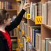 girl in library picking out book